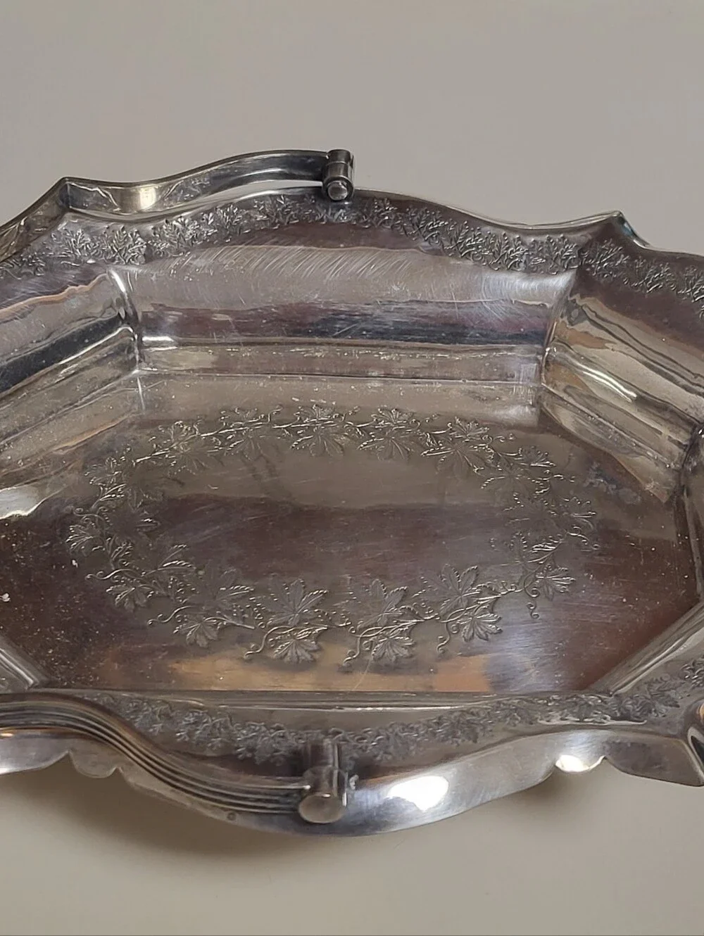 Silver-plated decorative tray with ornate scalloped rim and handles,